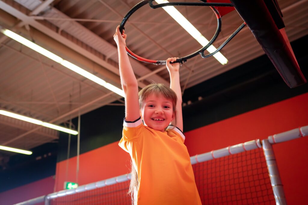 Happy child girl playing basketball and having fun in jump park